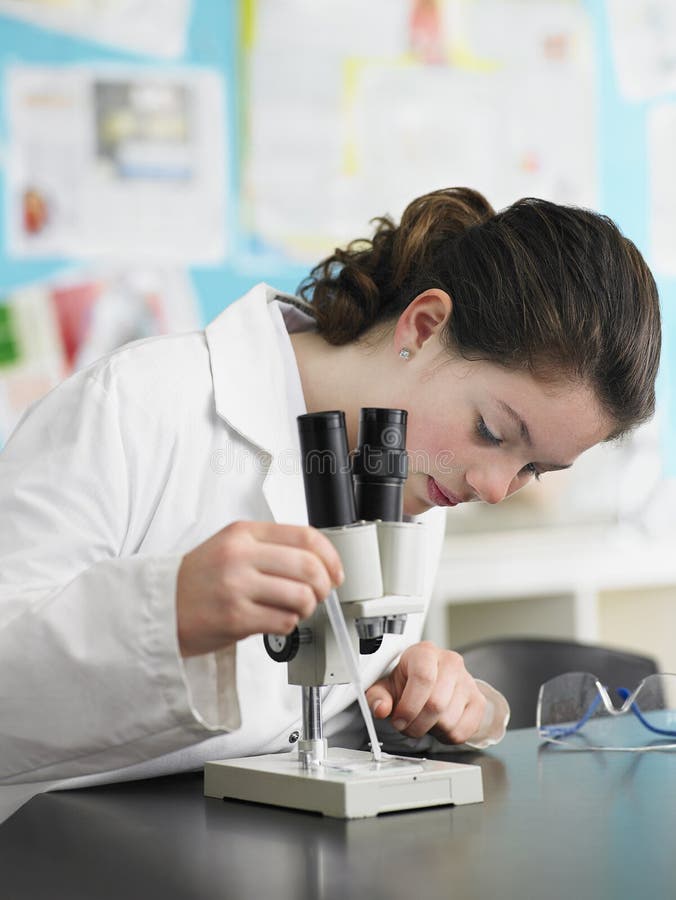 Teenage girl using microscope in laboratory