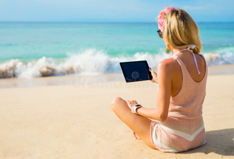 Girl using tablet on the beach stock photo