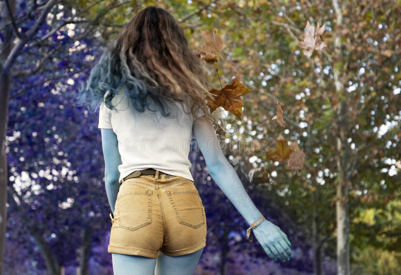 Girl walking back in an autumn landscape with purple tone in the park