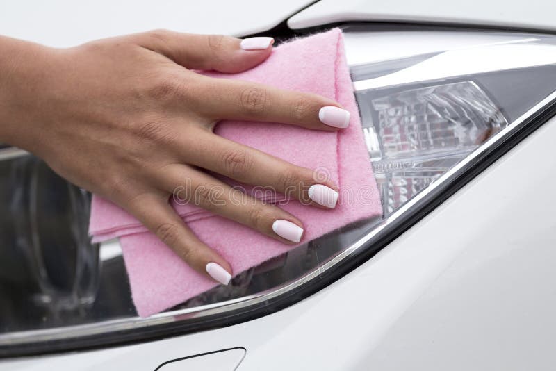 Woman`s hand with a cloth to clean the headlights of the car. Woman`s hand with a cloth to clean the headlights of the car