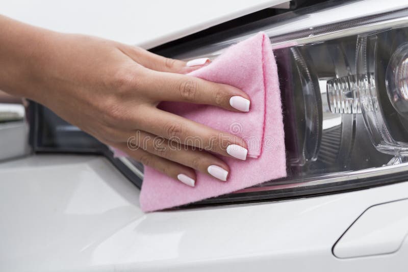 Woman`s hand with a cloth to clean the headlights of the car. Woman`s hand with a cloth to clean the headlights of the car