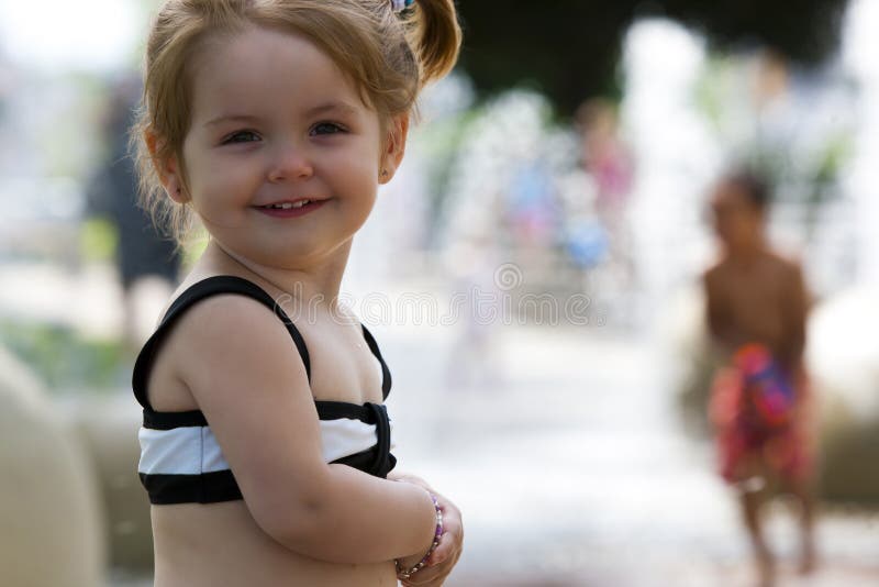 Una giovane ragazza gioca in sprinkler a un parco acquatico.