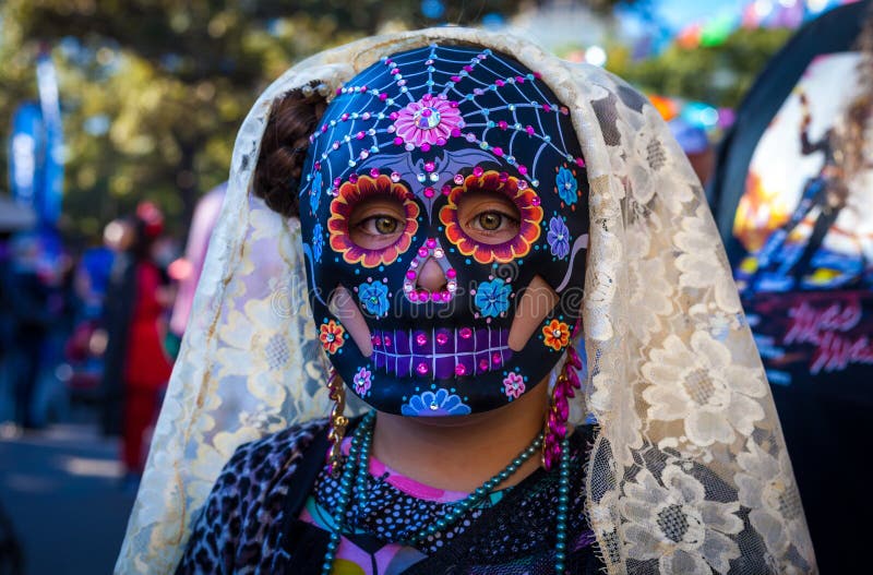 Girl wearing colorful sugar skull mask and lace veil for Dia de stock image