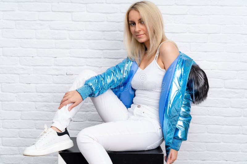 The girl is wearing white jeans, a white blouse, and a blue jacket with a fur hood on a white background. royalty free stock image