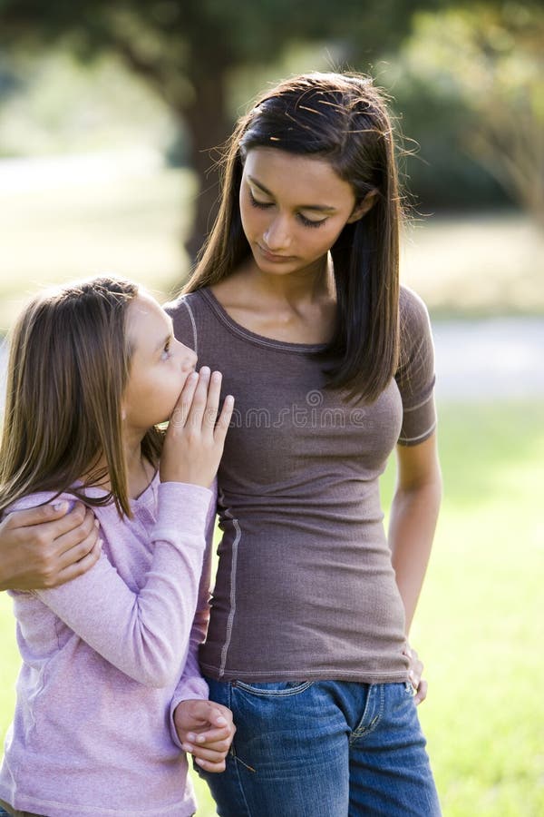 Girl whispering to her older teenage sister