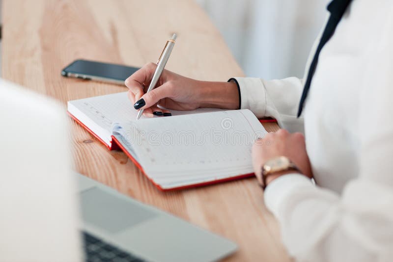 Girl in a white blouse sits at a table with a laptop and writes in a red notebook stock photography Girl in a white blouse sits at a table with a laptop and writes in a red notebook stock photography
