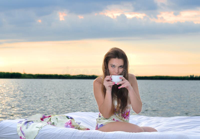 The girl woke up in a bed on water and drink cup of coffee royalty free stock photos