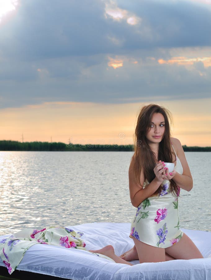 The girl woke up in a bed on water and drink cup of coffee stock photography