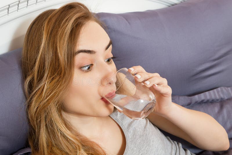 Girl woman drink water in bed at home, healthcare concept, hangover