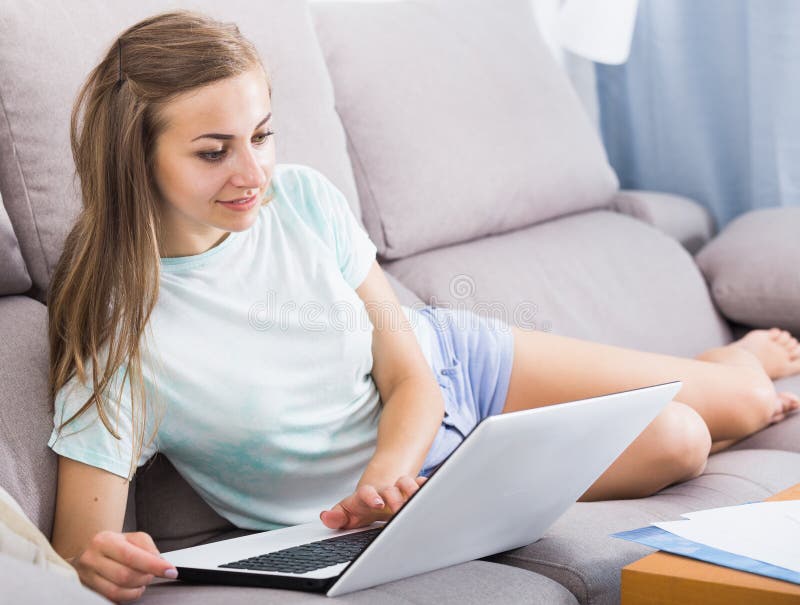 Girl is working on sofa with laptop