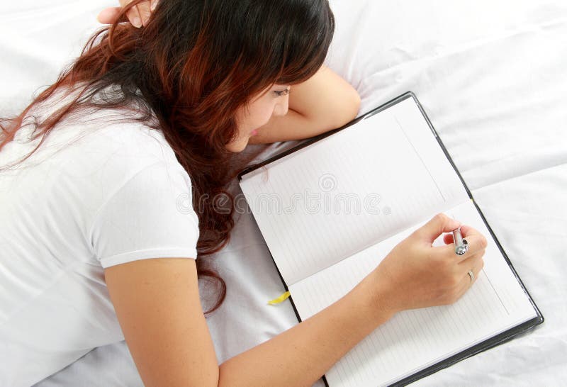 Girl writing book on the bed