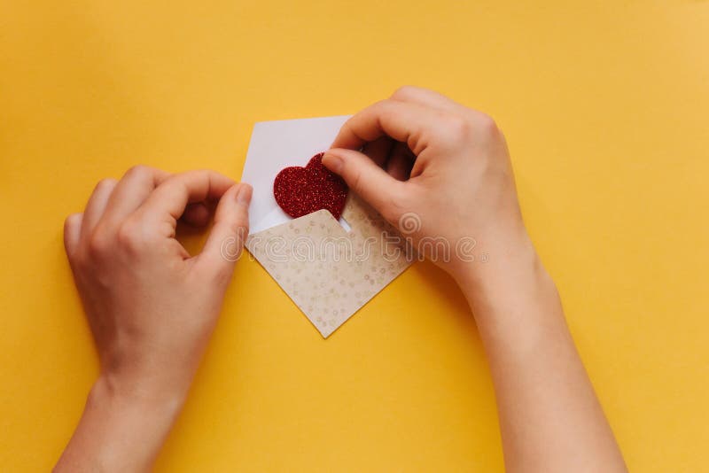 The girl wrote a letter with congratulations and pastes the envelope with a symbol in the form of a heart. Creative space stock image The girl wrote a letter with congratulations and pastes the envelope with a symbol in the form of a heart. Creative space stock image