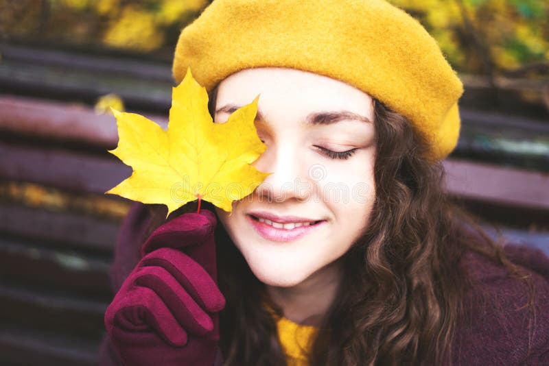 Girl in a yellow beret with maple leaf in her face. stock image Girl in a yellow beret with maple leaf in her face. stock image