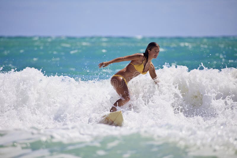 Girl in a yellow bikini surfing