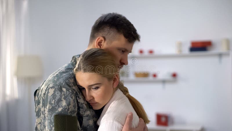 Girlfriend embracing upset boyfriend soldier, military service farewell, sadness