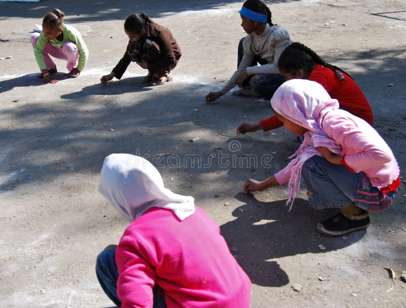 Girls drawing with chalk playing a game at playground at school stock photo Girls drawing with chalk playing a game at playground at school stock photo