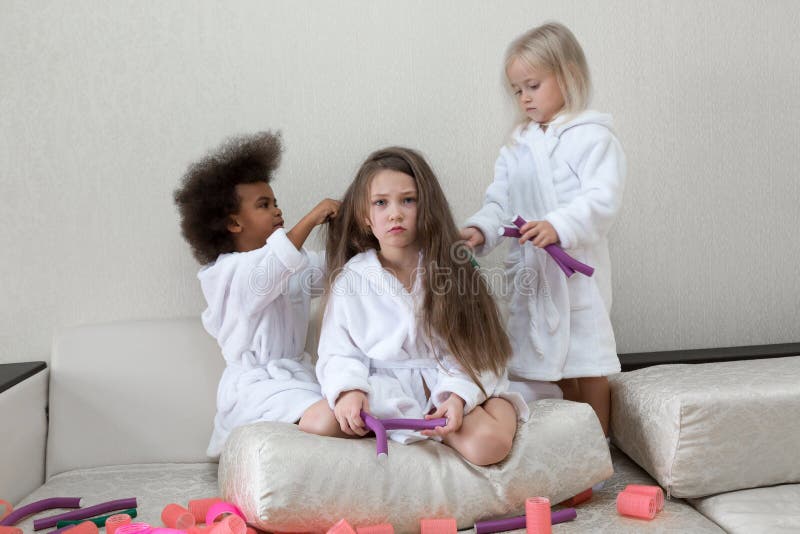 Little girls play with hair curlers and hairpins