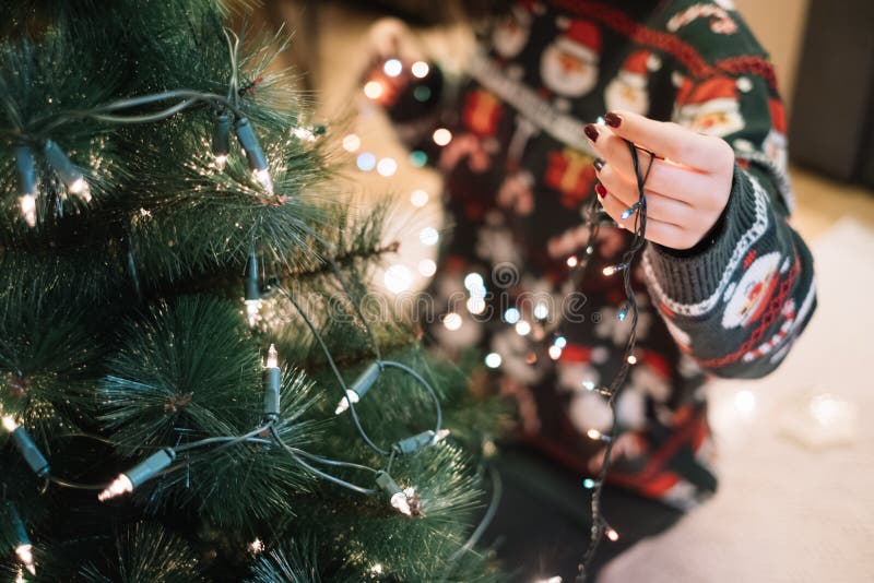 Girls hand putting Christmas lights to tree