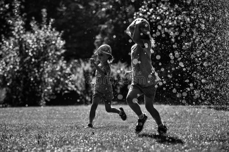 Girls are having fun in water in park, hot summer in garden, girls running in water drops, happy and cheerful girls enjoying water stock photos Girls are having fun in water in park, hot summer in garden, girls running in water drops, happy and cheerful girls enjoying water stock photos