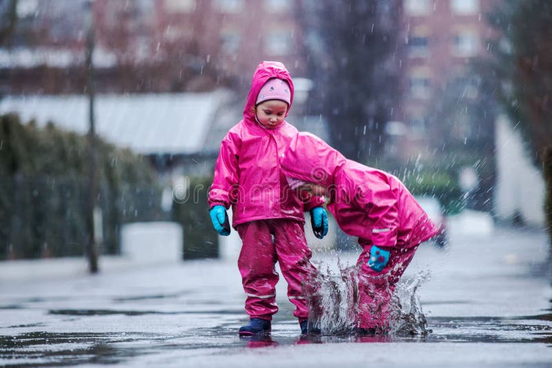 Girls are having fun in water on street in cold autumn day, girls splashing water in rain, cheerful girls enjoying cold weather