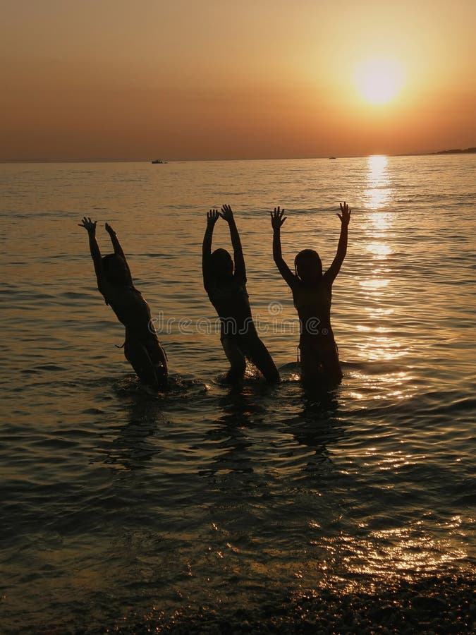 Girls jumping in the sea in sunset