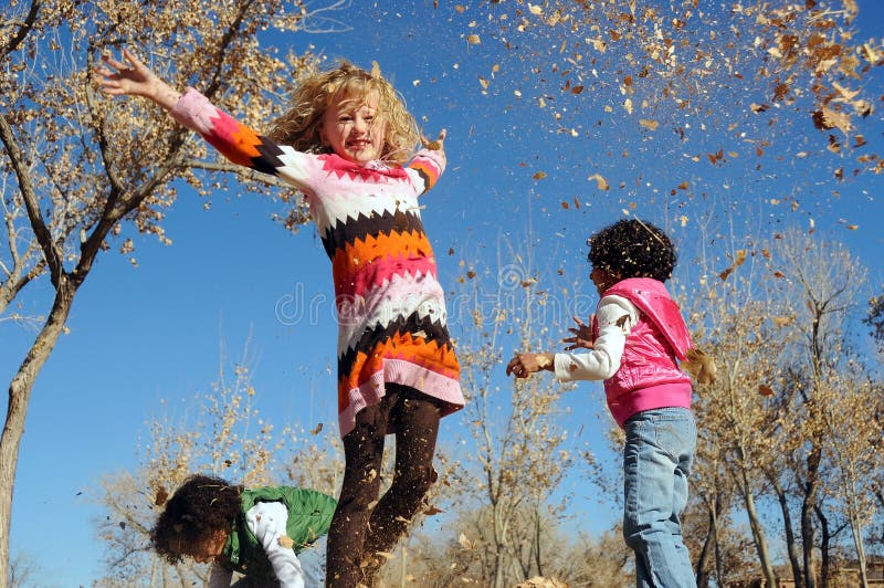 Joven las chicas en hojas sobre el soleado otono.