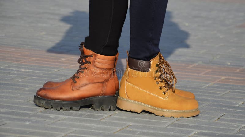 Girls in shoes are standing on the sidewalk tiles, in a Sunny evening