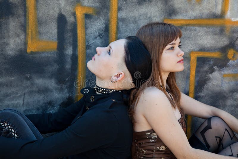 Girls sitting in front of graffiti wall