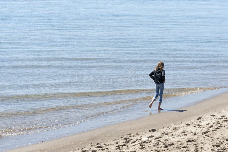 A preteen girl walks along the water`s edge of Siletz Bay in Lincoln City on the Oregon Coast. A preteen girl walks along the water`s edge of Siletz Bay in Lincoln City on the Oregon Coast