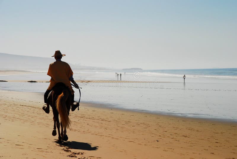 Giro del cavallo sulla spiaggia Taghazout Souss-Massa-Drâa morocco immagine stock libera da diritti Giro del cavallo sulla spiaggia Taghazout Souss-Massa-Drâa morocco immagine stock libera da diritti