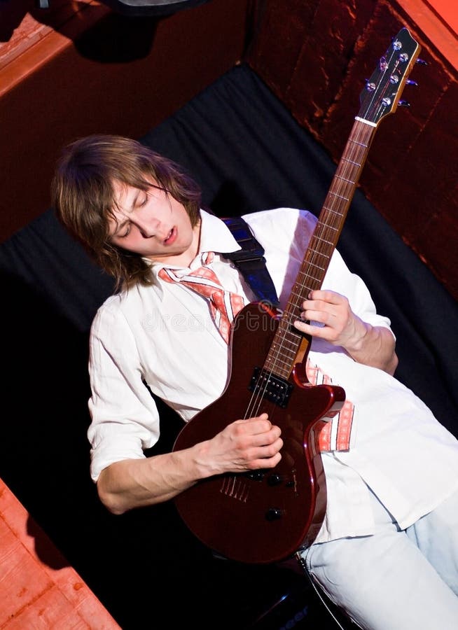 Young man in white shirt emotionally playing the guitar. Young man in white shirt emotionally playing the guitar