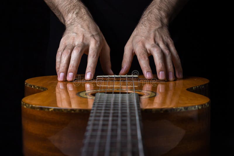 Gitarr på svart bakgrund. akustisk gitarr på mörk bakgrund. händer når för gitarren