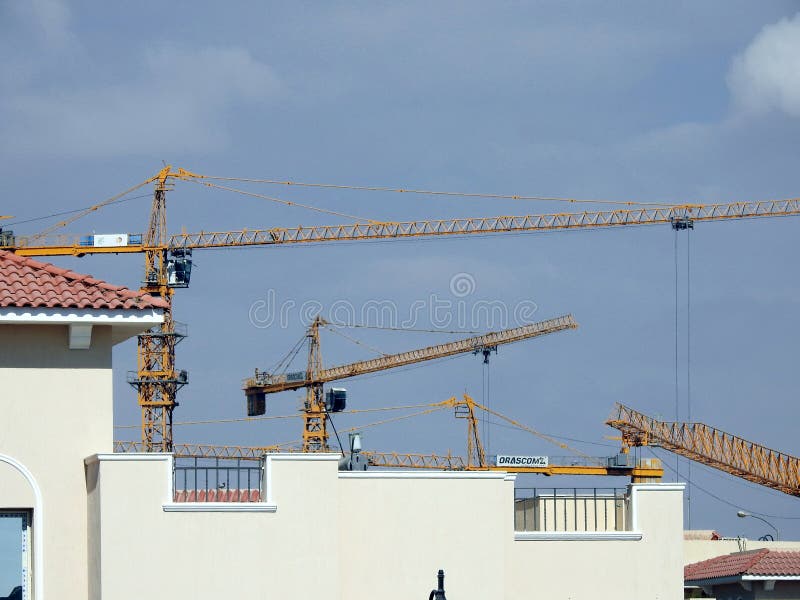 Giza, Egypt, March 28 2021: crane towers at a construction site of new high rise developmental residential buildings in Sheikh Zayed city, selective focus of cranes for new city building. Giza, Egypt, March 28 2021: crane towers at a construction site of new high rise developmental residential buildings in Sheikh Zayed city, selective focus of cranes for new city building