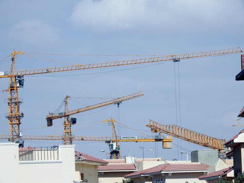 Giza, Egypt, March 28 2021: crane towers at a construction site of new high rise developmental residential buildings in Sheikh Zayed city, selective focus of cranes for new city building. Giza, Egypt, March 28 2021: crane towers at a construction site of new high rise developmental residential buildings in Sheikh Zayed city, selective focus of cranes for new city building