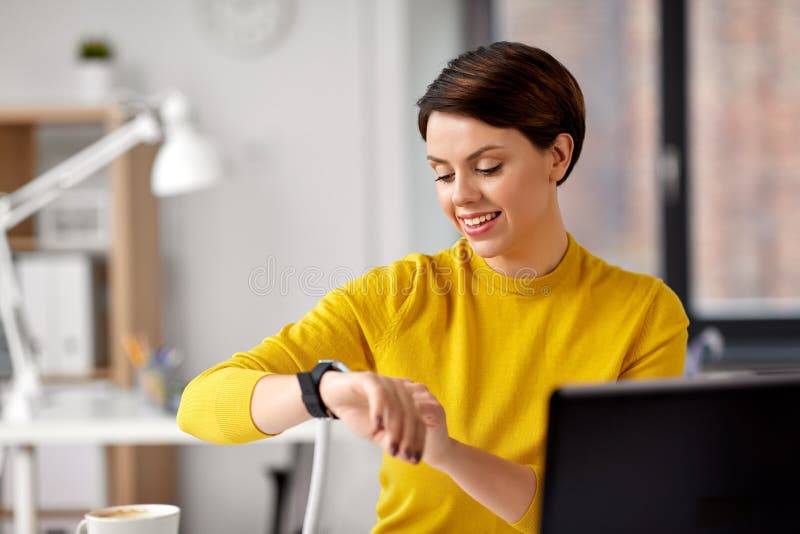 Gl?ckliche Gesch?ftsfrau, die intelligente Uhr im B?ro verwendet stockfotos Gl?ckliche Gesch?ftsfrau, die intelligente Uhr im B?ro verwendet stockfotos