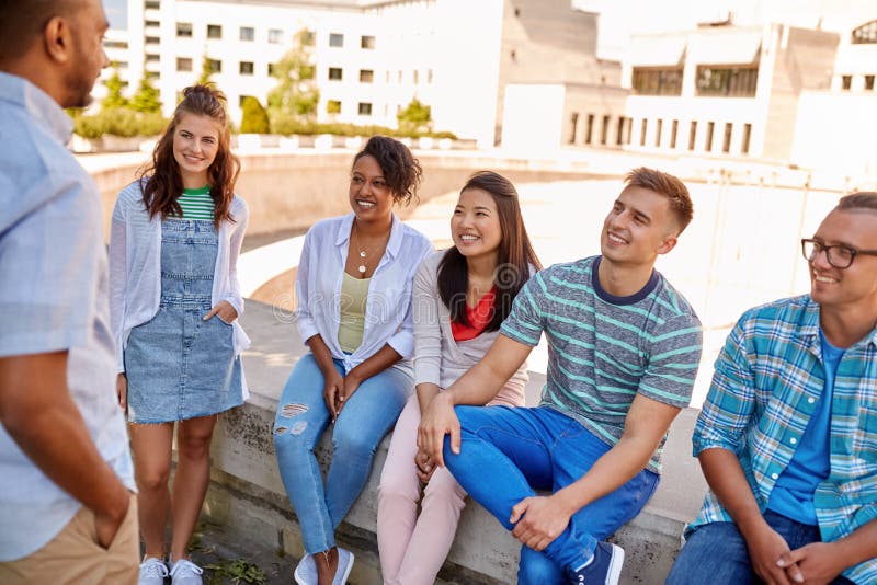 Gl? ckliche internationale Freunde, die in der Stadt sprechen stockbilder