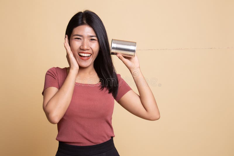 Gl? ckliche junge Asiatin mit Blechdosetelefon h? ren stockfotografie
