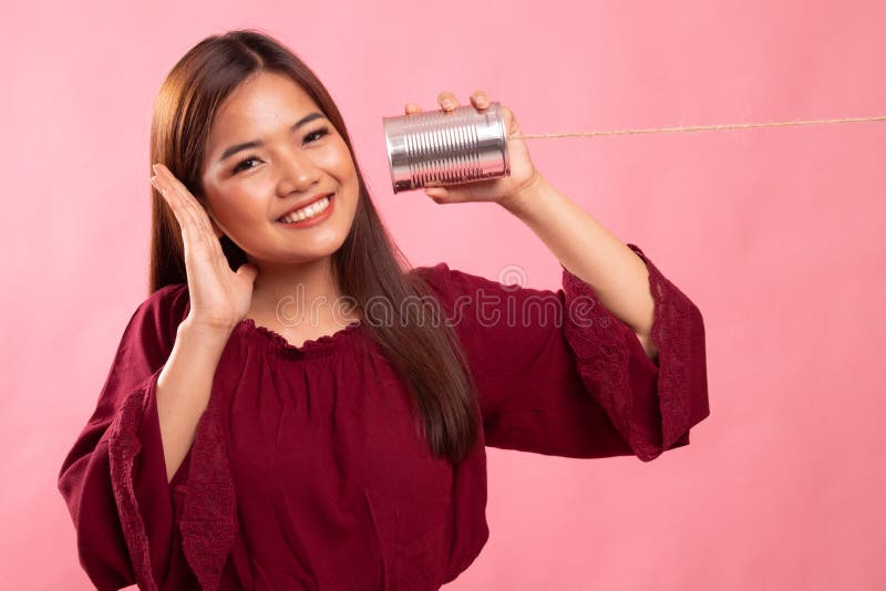Gl? ckliche junge Asiatin mit Blechdosetelefon h? ren lizenzfreies stockbild