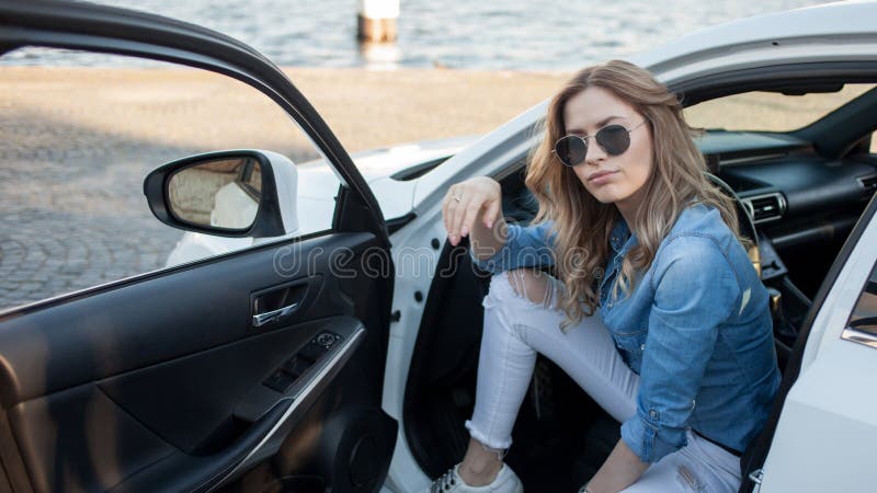 Gl?ckliche junge Blondine, die in einem wei?en Auto sitzen Portr?t einer erfolgreichen attraktiven Frau lizenzfreies stockfoto Gl?ckliche junge Blondine, die in einem wei?en Auto sitzen Portr?t einer erfolgreichen attraktiven Frau lizenzfreies stockfoto