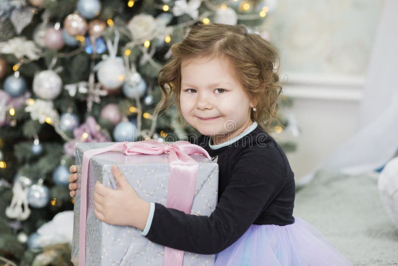 Gl? ckliches kleines M? dchen mit Weihnachtsgeschenk M? dchen erfreut mit Geschenk Nettes Kind, das sich nach Hause f? r Weihnachtsfe lizenzfreie stockfotos