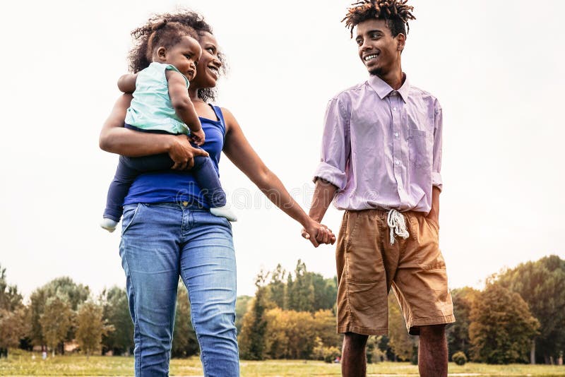 Glad afrikansk familj som går samman i en offentlig park - mor, far och barndotter har kul under en veckodag. arkivbilder Glad afrikansk familj som går samman i en offentlig park - mor, far och barndotter har kul under en veckodag. arkivbilder