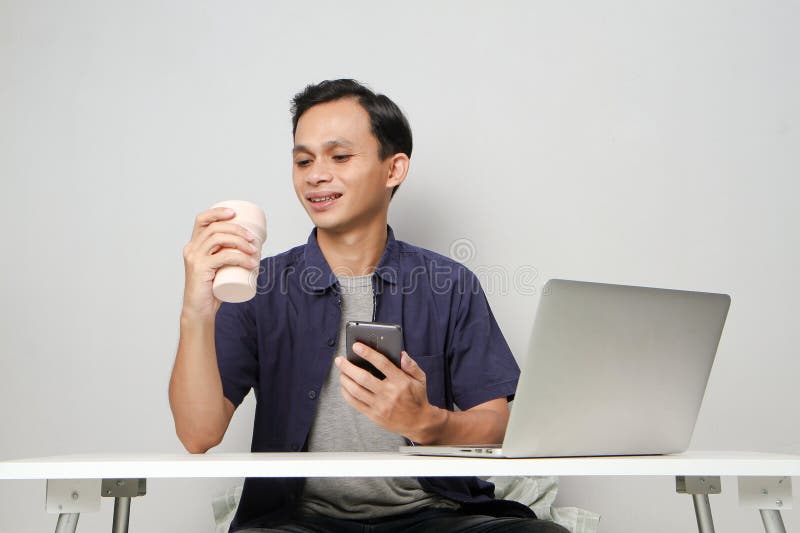 Glad att ha mobiltelefon medan du sitter framför datorn. på isolerad bakgrund royaltyfri foto