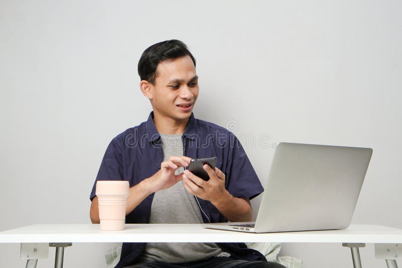 Glad att ha mobiltelefon medan du sitter framför datorn. på isolerad bakgrund royaltyfria bilder