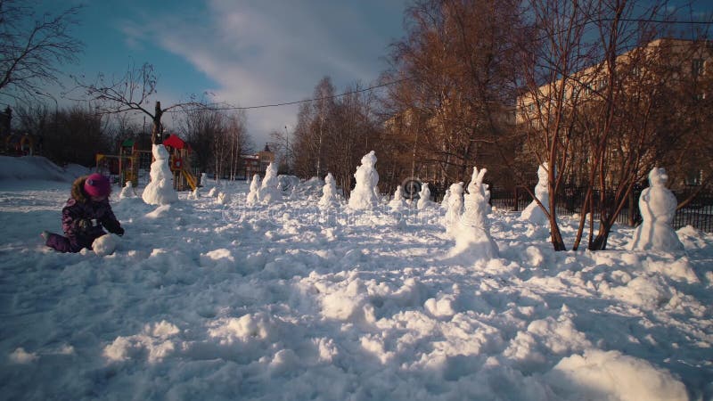 Glad barn gör snöman på den soliga vinterdagen