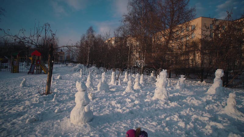 Glad barn gör snöman på den soliga vinterdagen