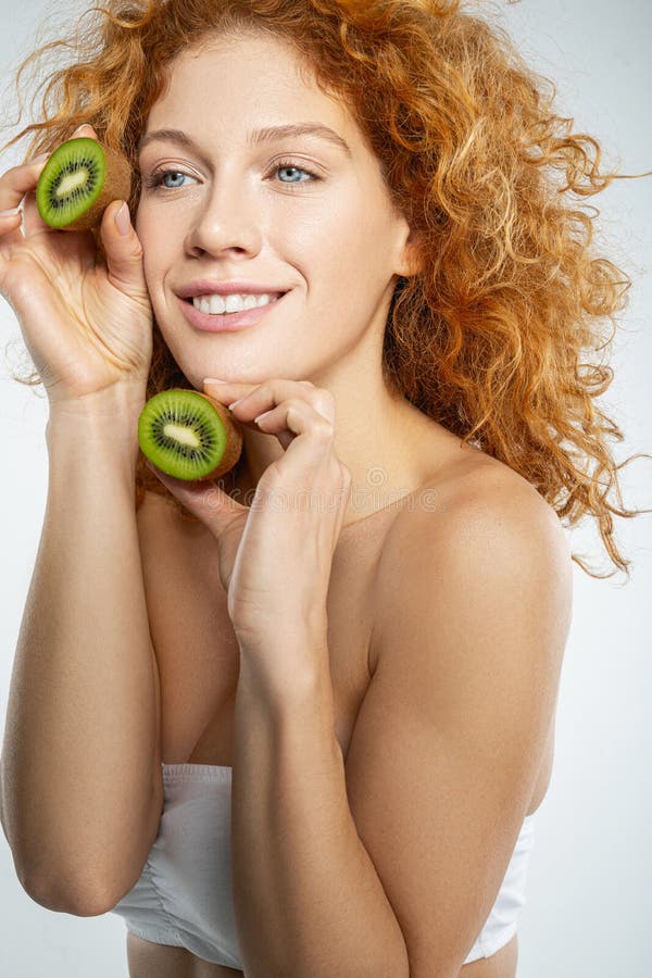 Glad, glad dam som håller kiwi i händerna fotografering för bildbyråer