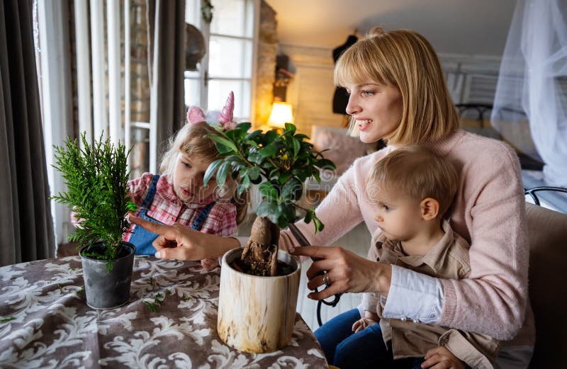Glad ensamstående förälder med en liten son planterar husväxter hemma. Trädgårdsverksamhet i hemmet arkivbild