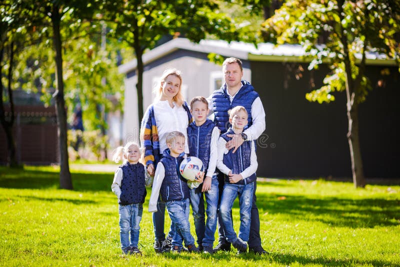 Glad familj utomhus Glad kaukasisk familj som står utanför sitt hus och kramar Familj med fyra barn i framhuset royaltyfria bilder Glad familj utomhus Glad kaukasisk familj som står utanför sitt hus och kramar Familj med fyra barn i framhuset royaltyfria bilder