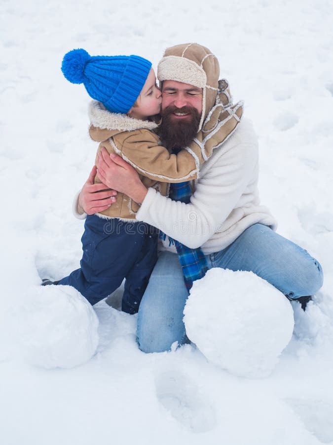 Glad far och son som gör snöman i snö Pappa och son ler och kramar Bästa vinterspel för lyckliga familjer royaltyfria foton
