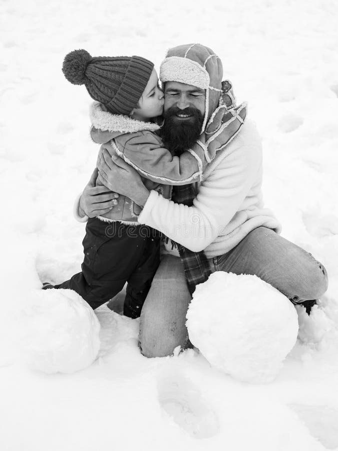 Glad far och son som gör snöman i snö Pappa och son ler och kramar Bästa vinterspel för lyckliga familjer royaltyfri fotografi